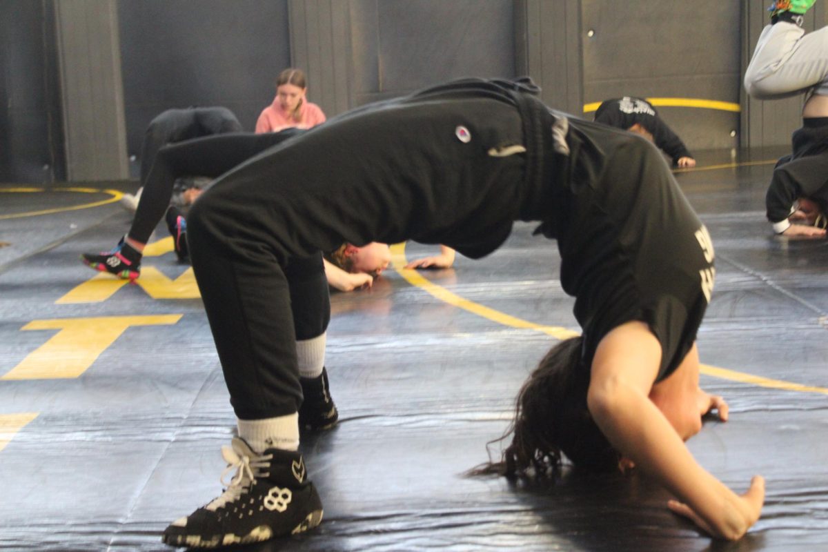 Lily Johnson holds a bridge position during girls’ wrestling practice. She pushed through the drill and focused on building strength and control.