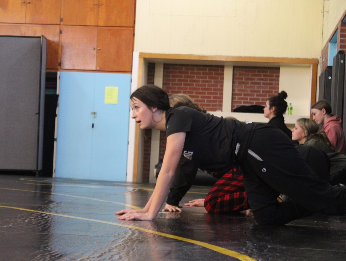 Lily Johnson watches intently as a warm-up game begins. The players wrestled and tackled each other as they fought to grab a ball. once someone secured it, they sprinted to throw the ball at the target while the others tried to stop them.

