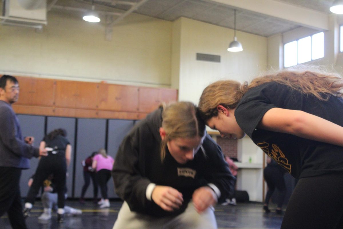 Cadence Kinzie locks in head-to-head with a middle schooler as they run a drill at wrestling practice.
They concentrated on their stance and reacted to each other’s movement.