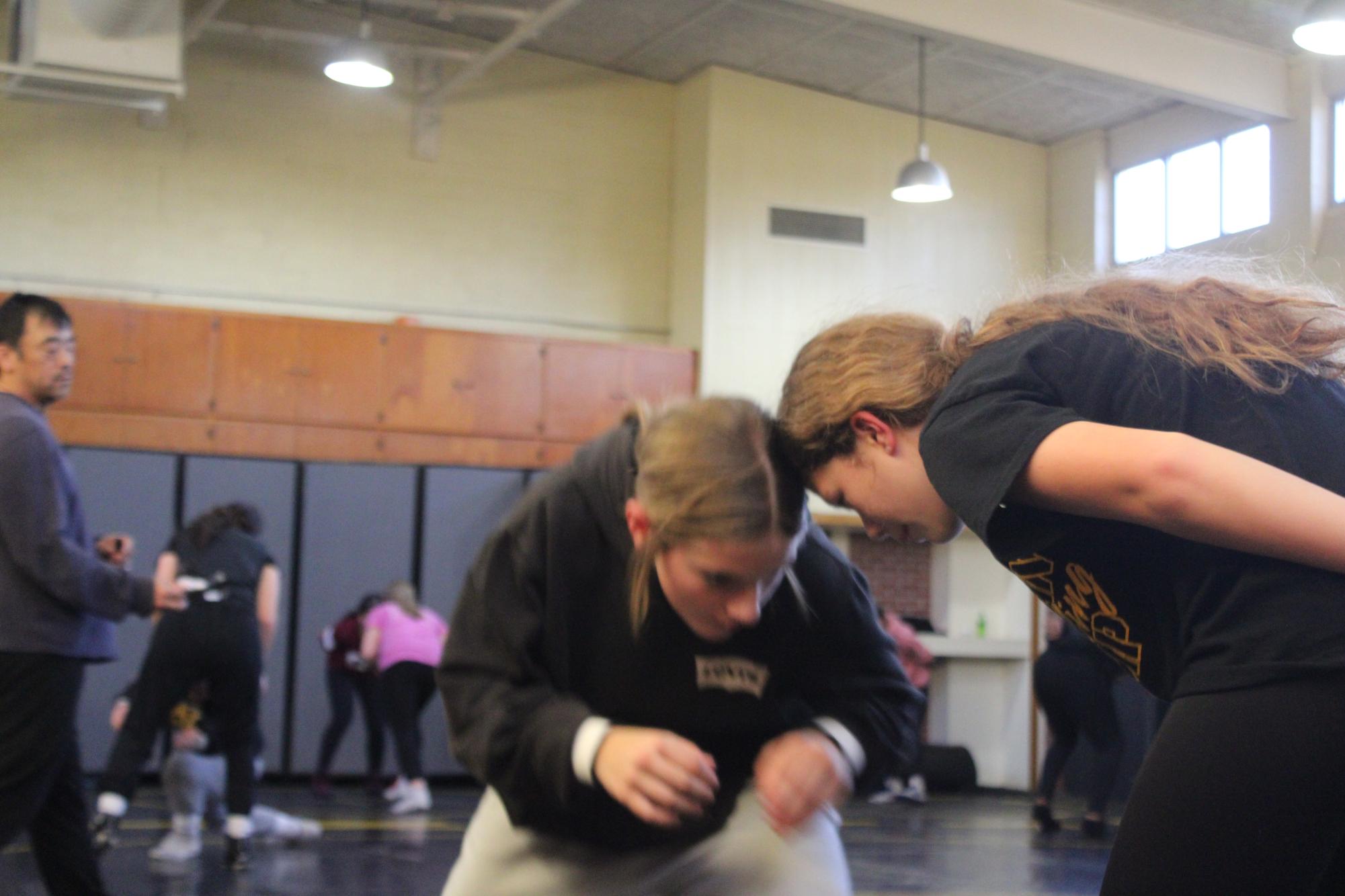 Cadence Kinzie locks in head-to-head with a middle schooler as they run a drill at wrestling practice.
They concentrated on their stance and reacted to each other’s movement.