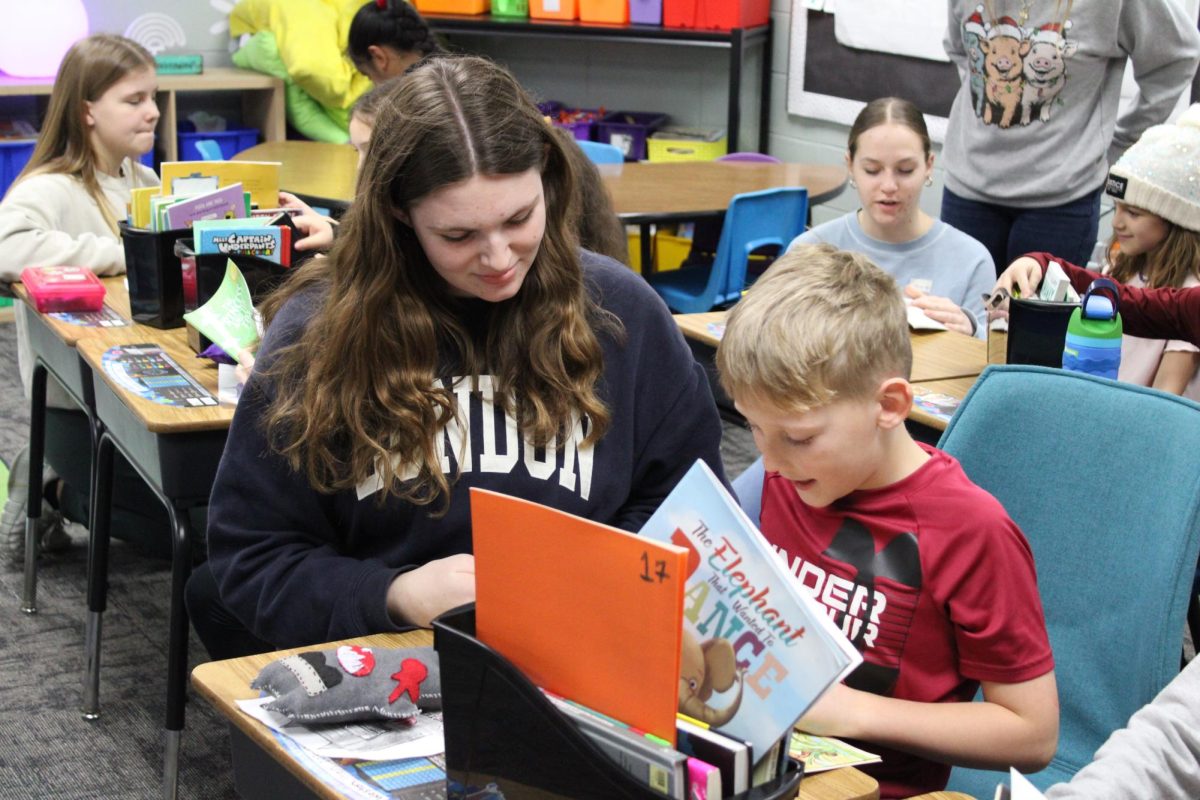 Sophomore Norah Olsen handed the stuffed monsters to the kid.she started to pick a book for the kid, so she could read to him.