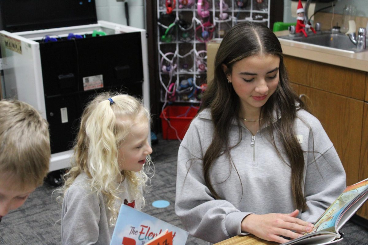 Freshman Willa Reid is reading a book to her 2nd grade partner.