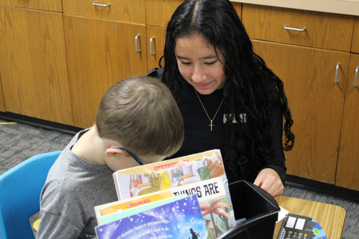 Freshman Ximena Mendez Cordero helps a child choose his book.