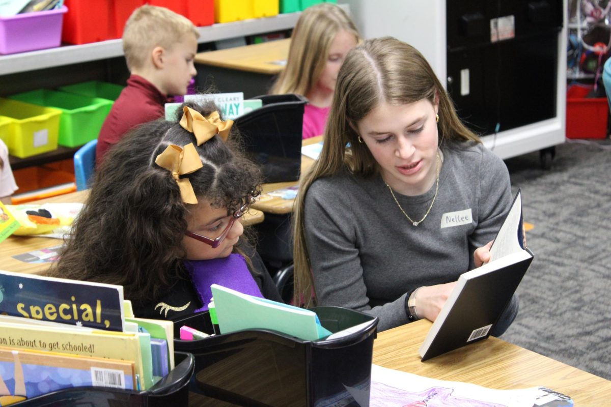 Freshman Nellee Ridder reads to a student after presenting her with her monster. The children asked questions. The second-graders also read to the FCS students.