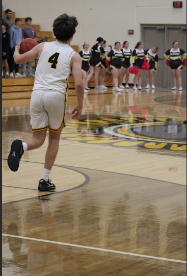 Point guard Hudson McLaren hustles down the court bringing the ball to start an offense. The defenders were in half court so he had low pressure as he jogged to Trojan territory. 
