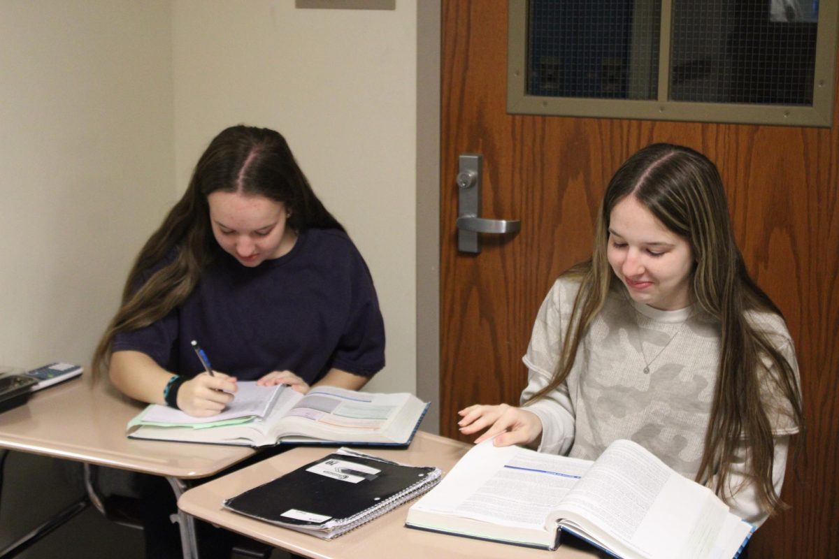 Seniors Kenzie and Keely Swanson work on her homework quietly in the hallway. 