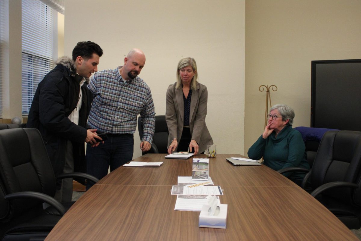 School board members leave the Feb. 4th meeting. A member of the press stands at the table with them.