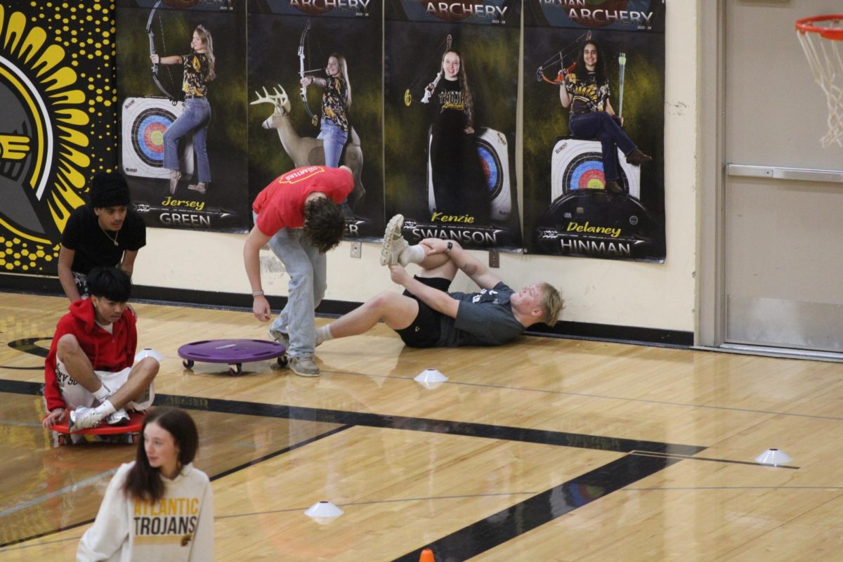Senior Keston Schmitt hurls seniors Cooper Woolsey off the cart and takes his place. The game invoved team members taking turns on the scooters.