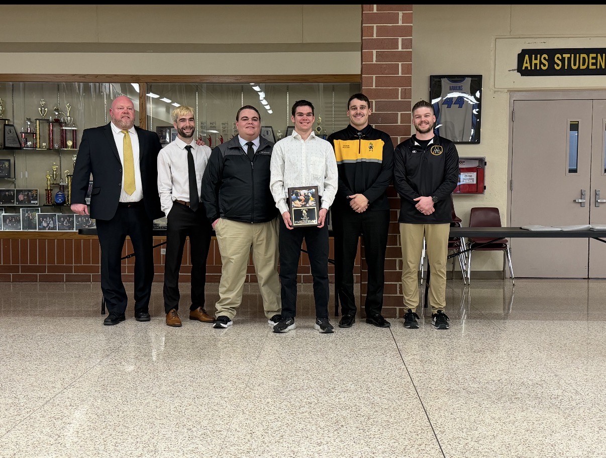 Dart Hansen stands in front of the coaching staff to receive his award.