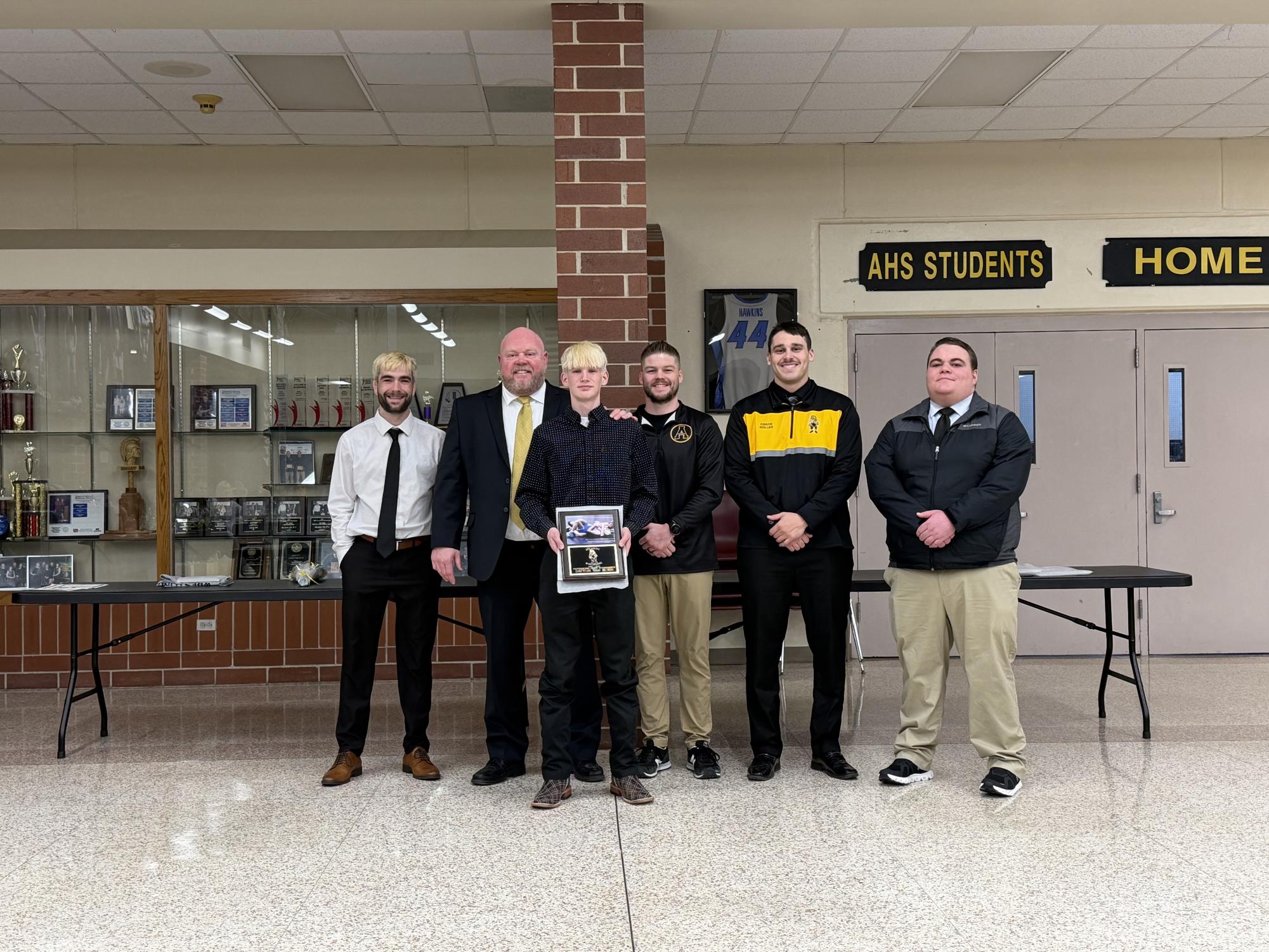 Junior Dayton Van Horn stands in front of the wrestling coaches after being presented with their award.