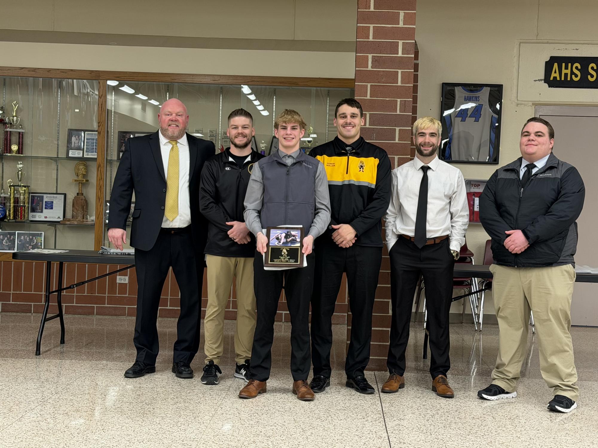 Senior Braxton Hass stands in front of the wrestling coaches after being presented with their award.
