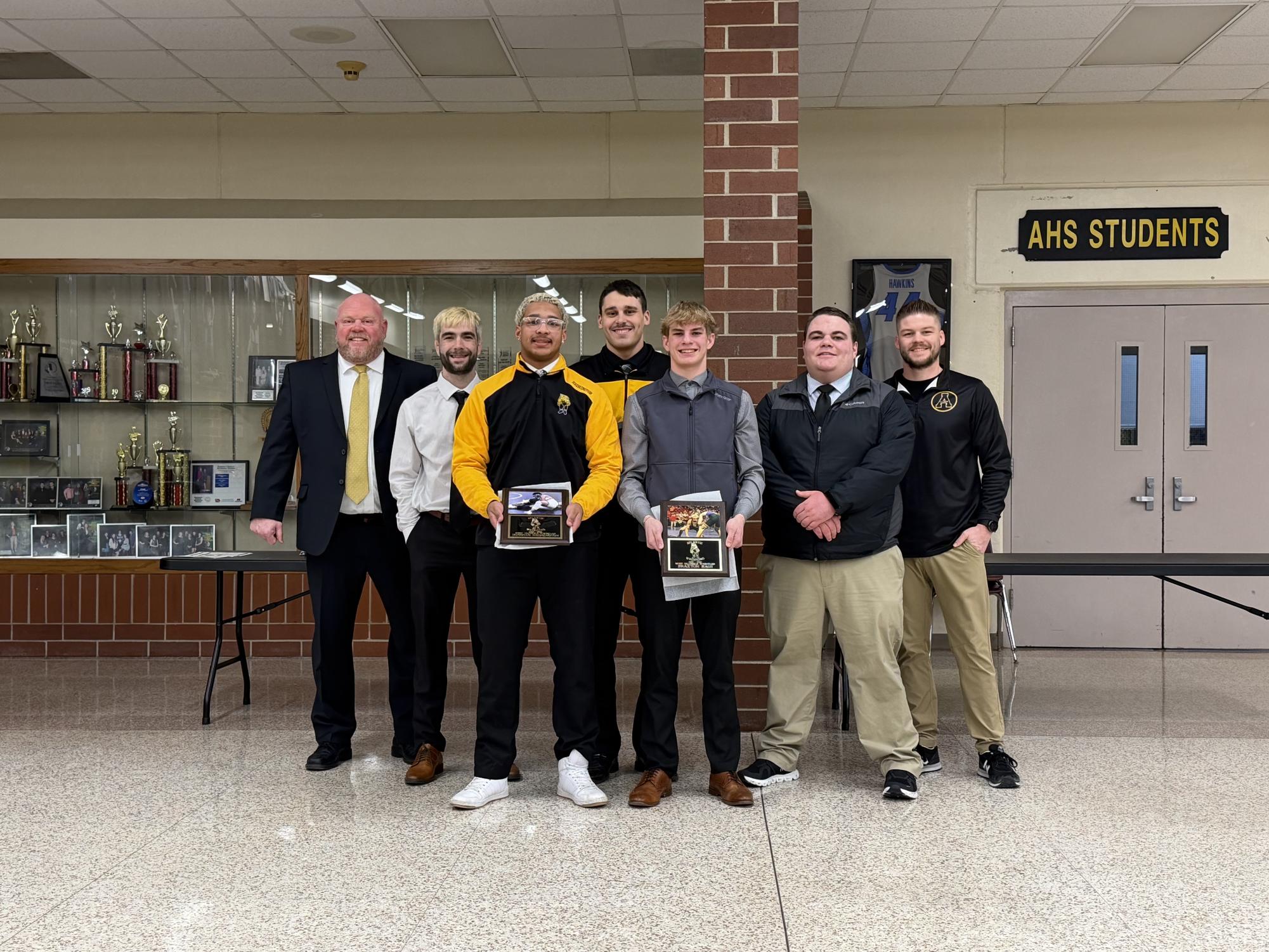 Team Captains Donovan Hedrington and Braxton Hass stand in front of the wrestling coaches after being presented with their award.