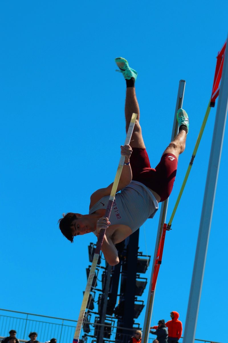Athlete clearing the bar in a competitive pole vault flight. 