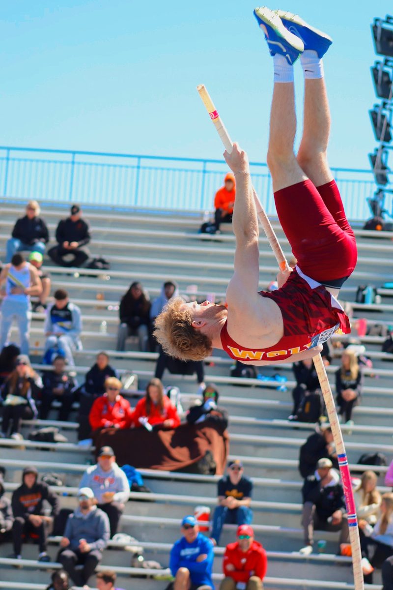 College athlete using his strength to thrust upwards to clear the pole vault bar. 