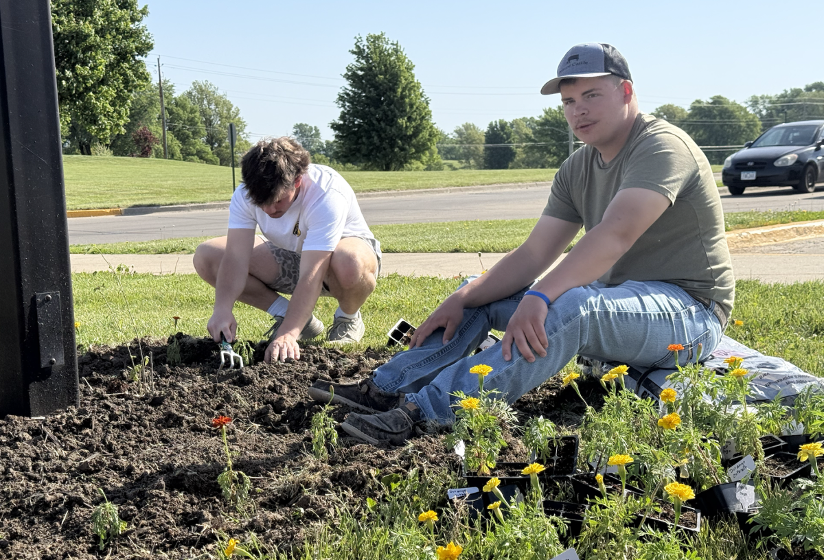 Jake Wailes and Hade Devore are busy planting flowers out front. Using a wide variety of tools and different flowers, the two create a plentiful flower bed. Wailes states, "have to make 'er pretty for this weekend."