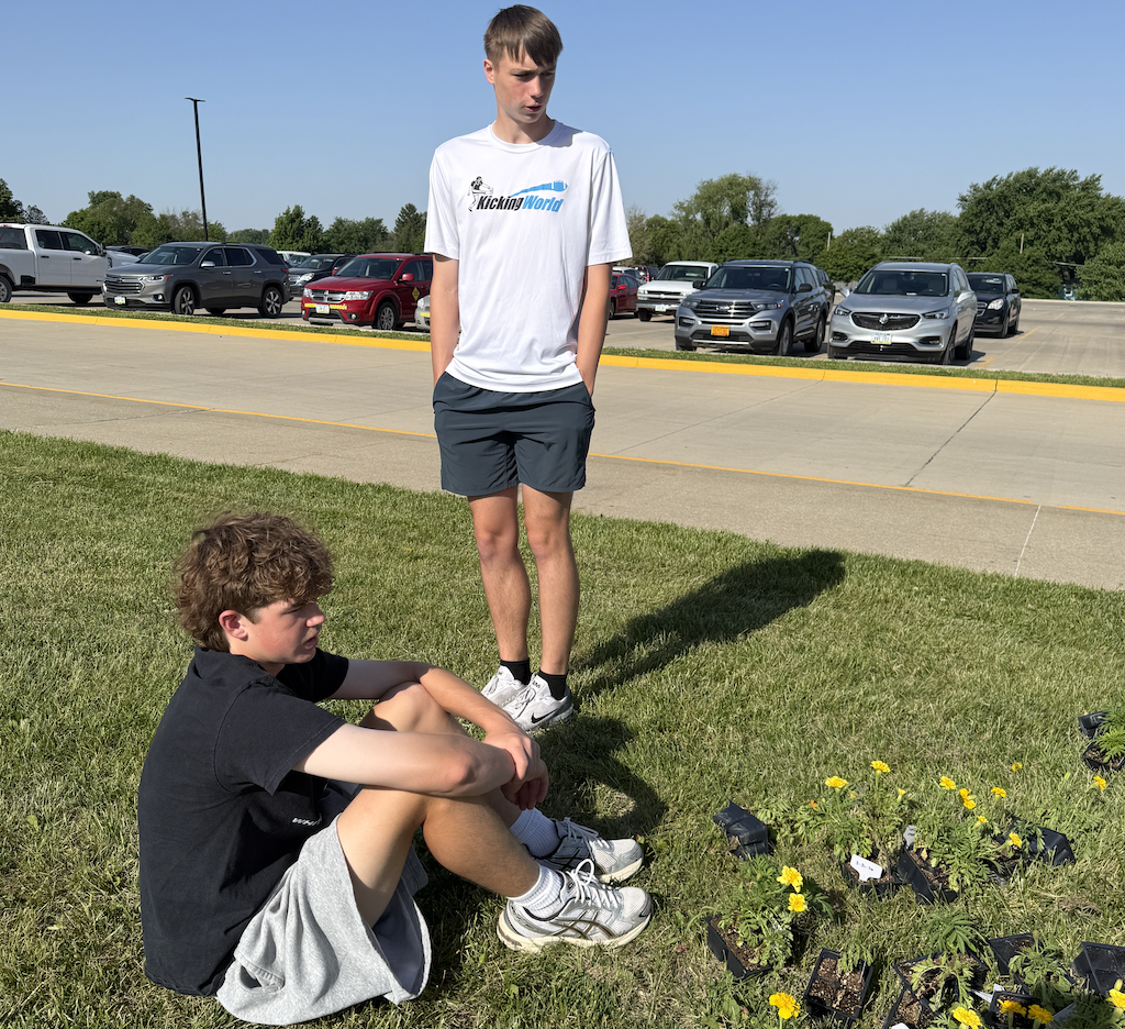 Gage Gross and Trevor Ellison watch as their garden plot has mulch added to it. Their flowers are prepared to be planted (in the bottom right). 